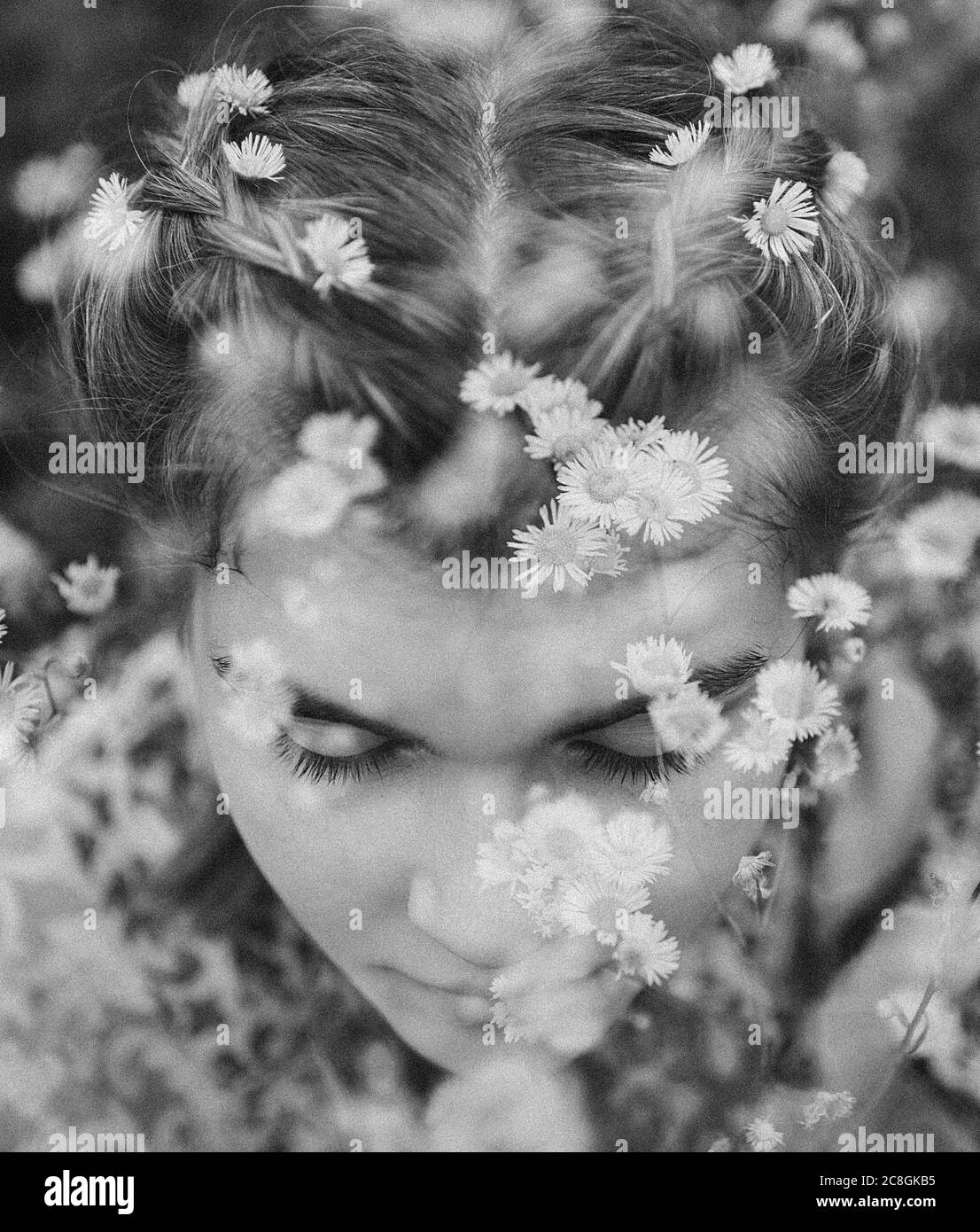 Young girl sitting in field of daisies Stock Photo