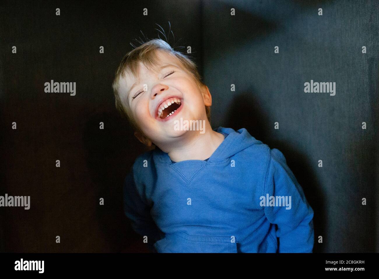 Joyful and happy toddler boy tilts head back while laughing indoors Stock Photo Alamy