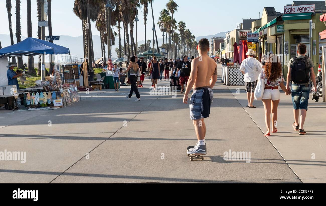 Young man on a skateboard through the famous boardwalk lined with lots
