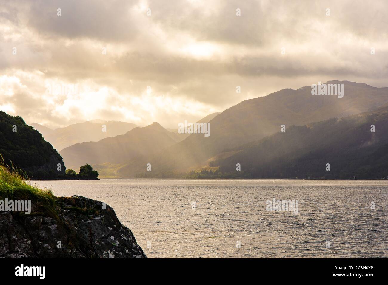 Dornie, SCOTLAND: Sunbeams filtering through the clouds over the lake surrounding Eilean Donan Castle. Stock Photo