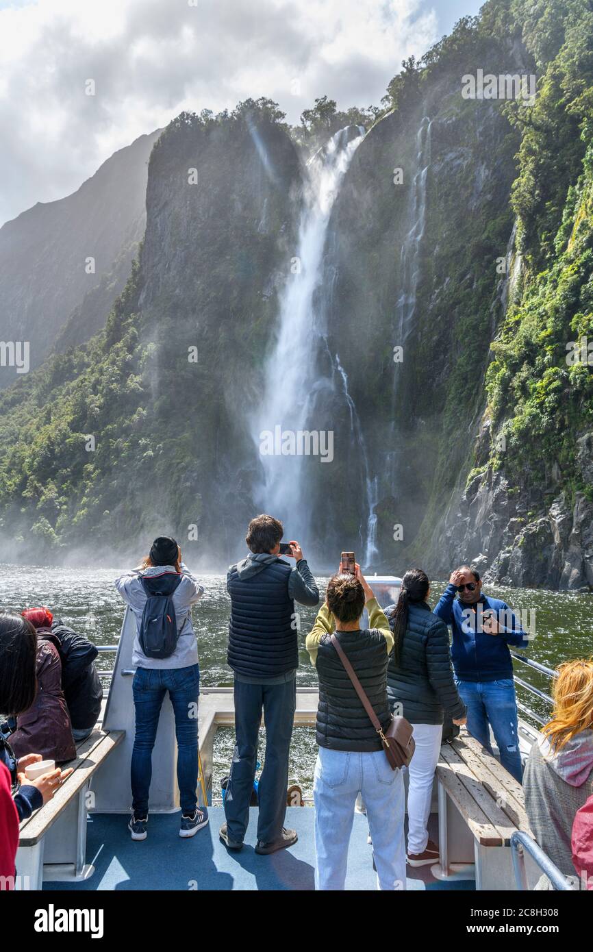 Tourists photographing Stirling Falls from the deck of a cruise boat, Milford Sound, Fiordland National Park, South Island, New Zealand Stock Photo
