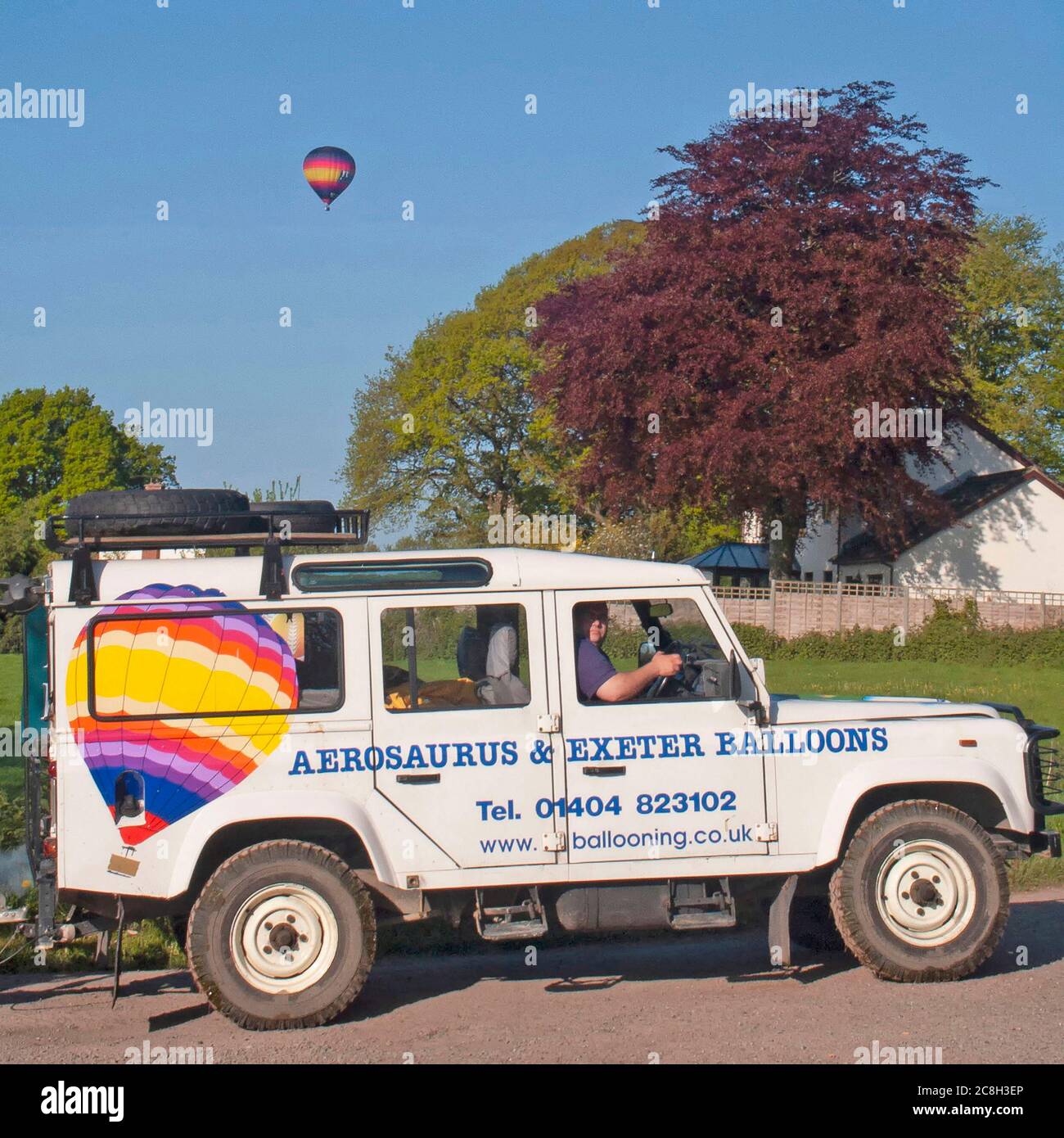 Hot air ballooning business company monitoring flight of a colourful balloon from Land Rover defender vehicle in country lane in Somerset England UK Stock Photo