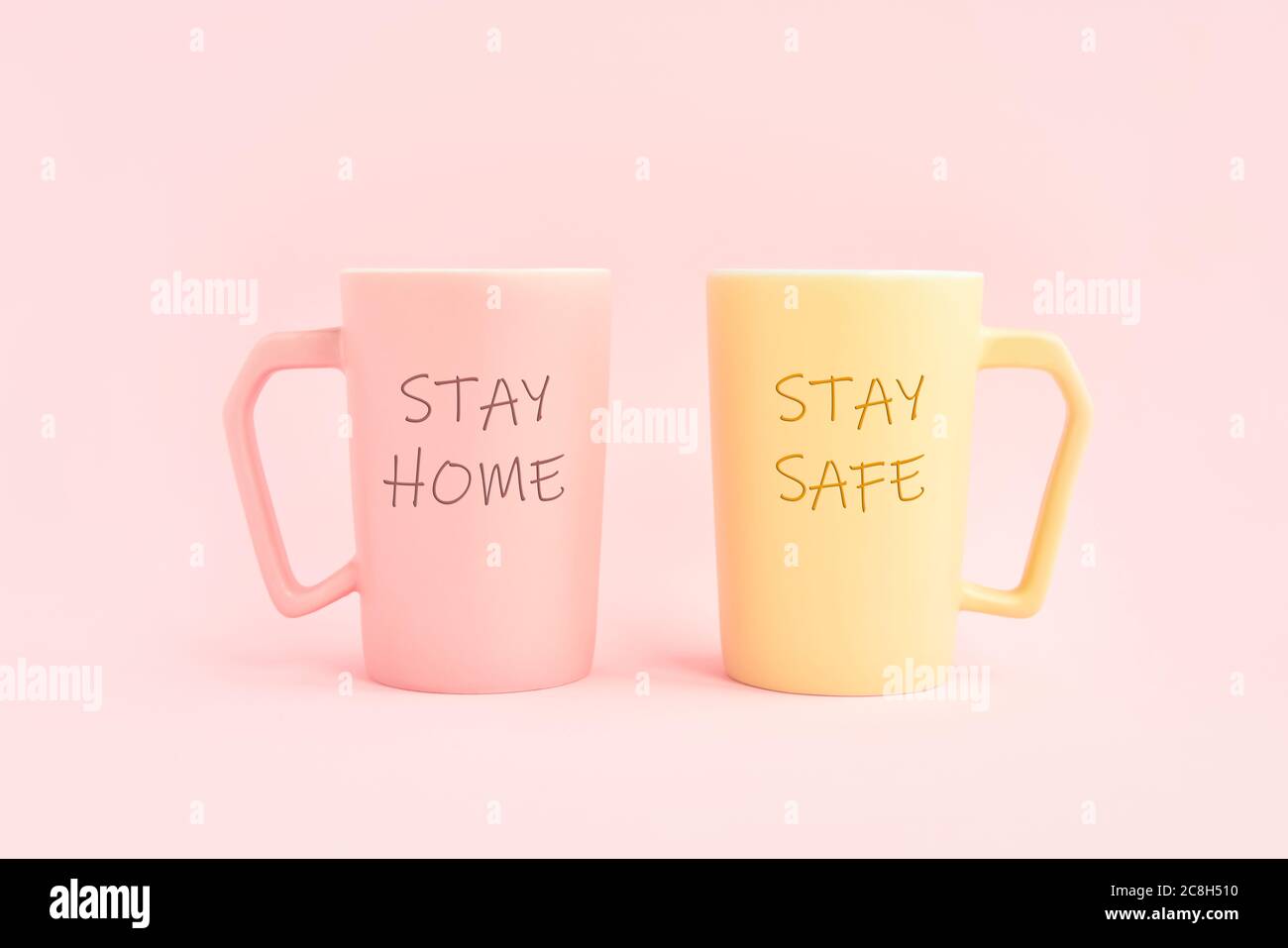 STAY HOME and STAY SAFE written on two cups of coffee on a pink background. Healthcare, medical and quarantine concept. Copy space for text Stock Photo