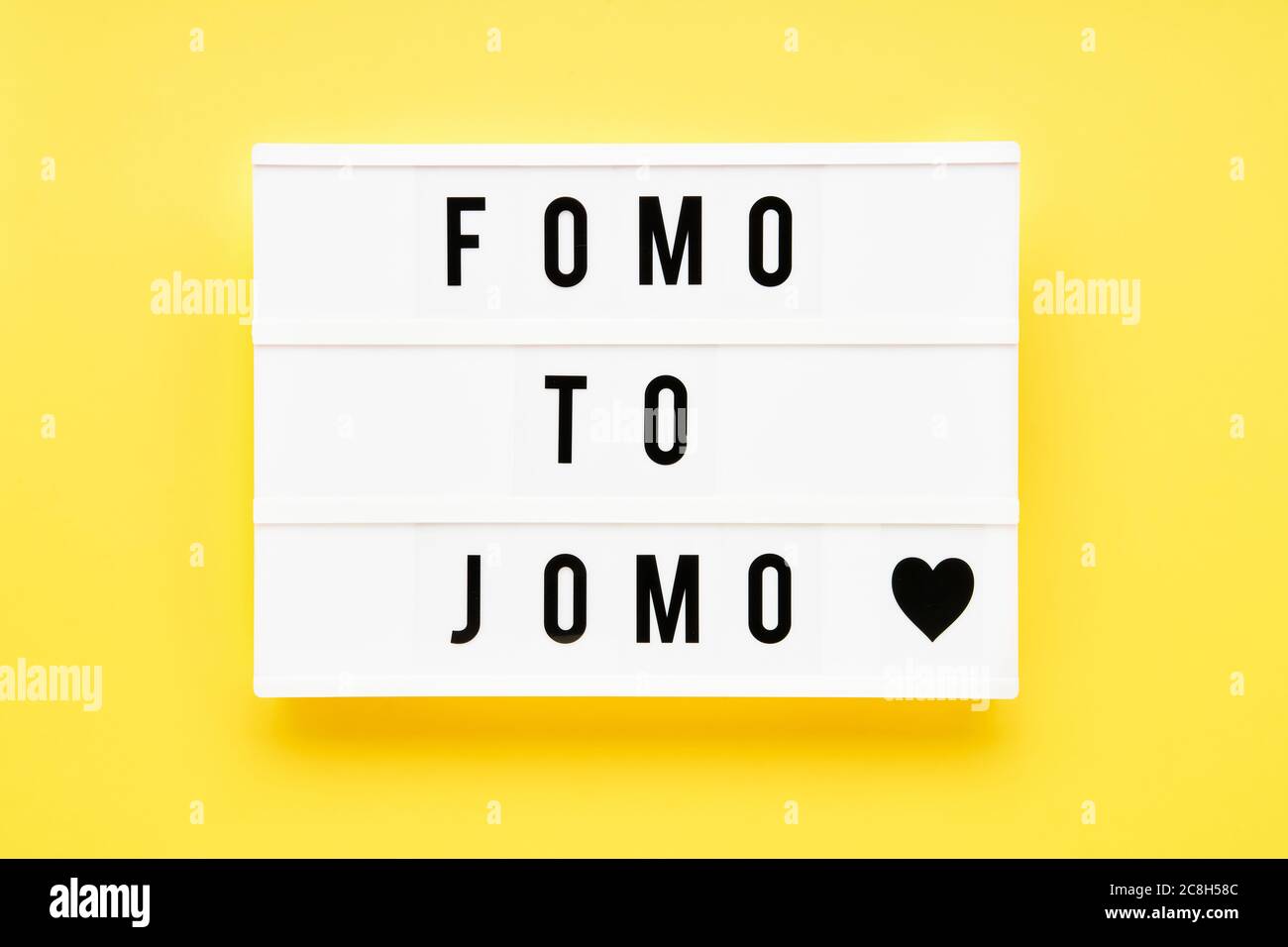 FOMO TO JOMO written in light box on yellow background. Choice, social problem concept. Top view, copy space Stock Photo
