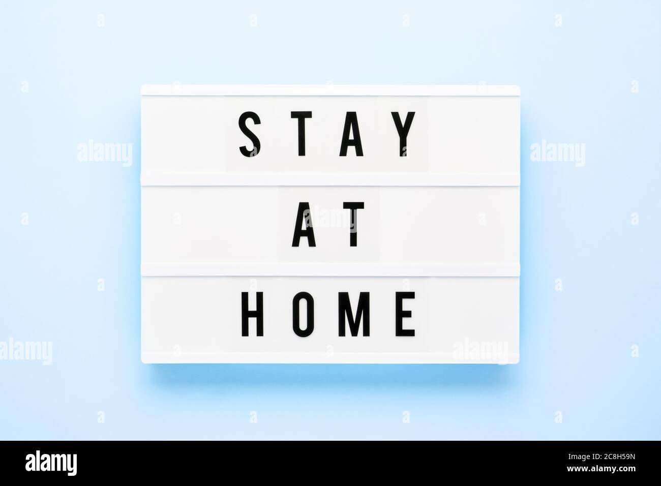 STAY AT HOME written in light box on blue background. Healthcare and medical concept. Top view, copy space. Quarantine concept. Stock Photo