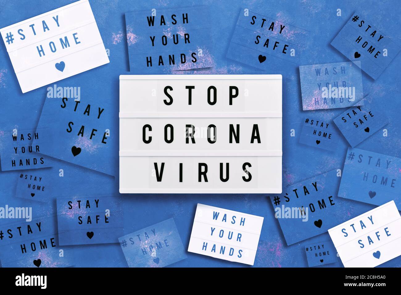 STOP CORONA VIRUS, STAY HOME, STAY SAFE and WASH YOUR HANDS written in light box on blue background. Healthcare and medical concept. Top view. Quarant Stock Photo