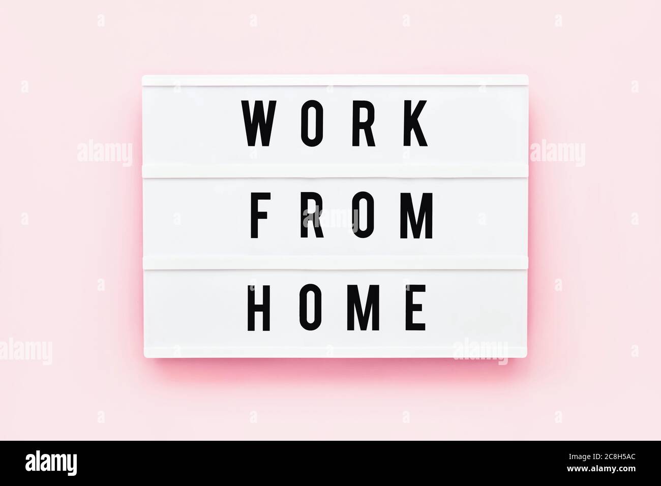 WORK FROM HOME written in light box on pink background. Healthcare and medical concept. Top view. Quarantine concept. Stock Photo
