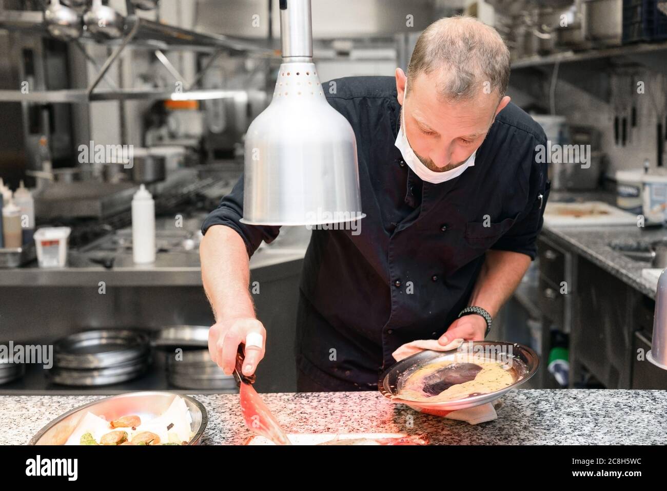 Chef in uniform cooking in a commercial kitchen. Male cook standing by ...