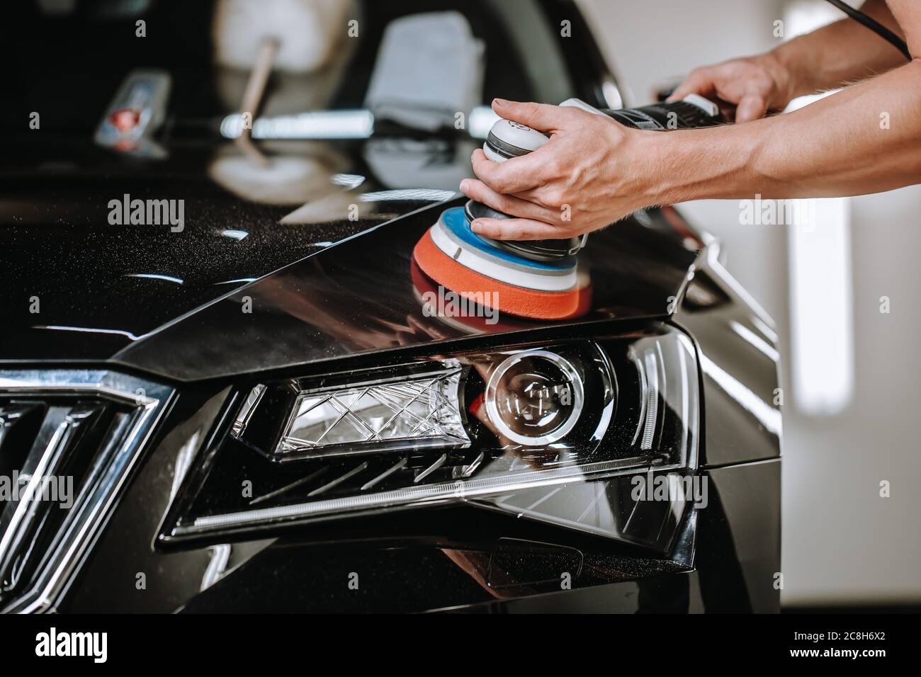 Professional detailing a car in car studio, hands with orbital polisher