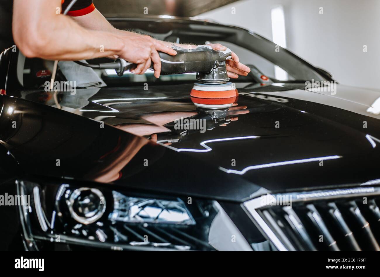Professional detailing a car in car studio, hands with orbital polisher