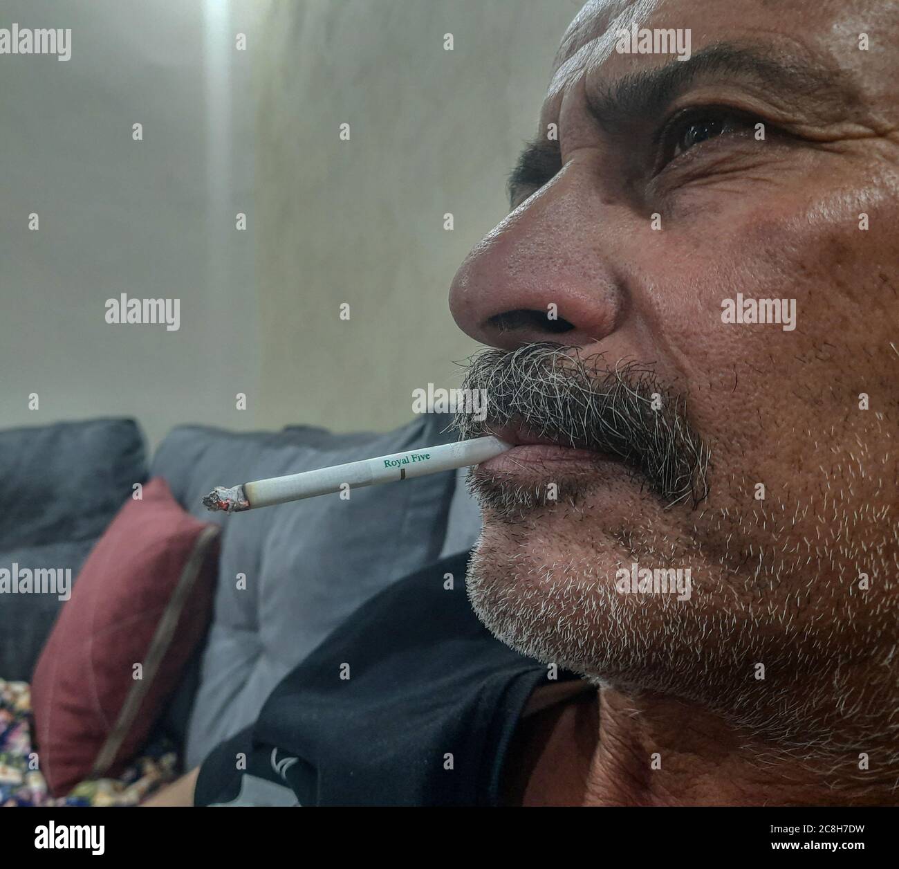 an elderly person is smoking while watching T.V Stock Photo