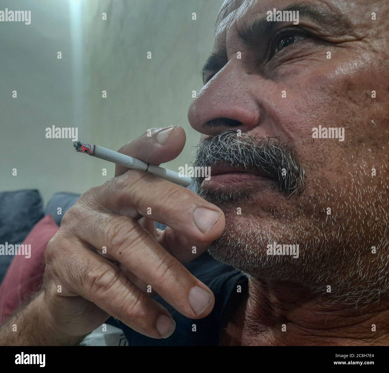 an elderly person is smoking while watching T.V Stock Photo