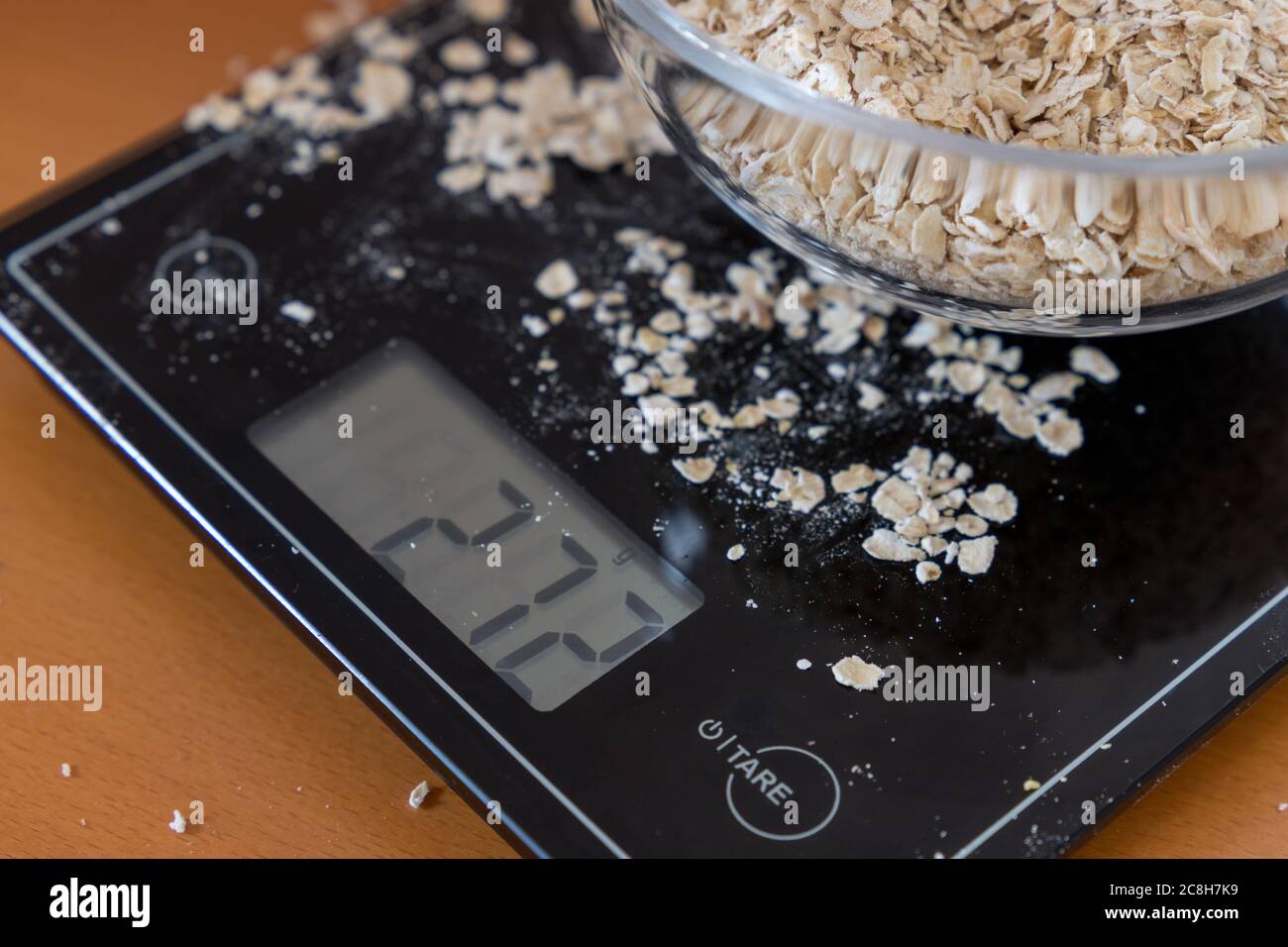 a digital kitchen scale shows the gram of a glass bowl with porridge oats on a display Stock Photo
