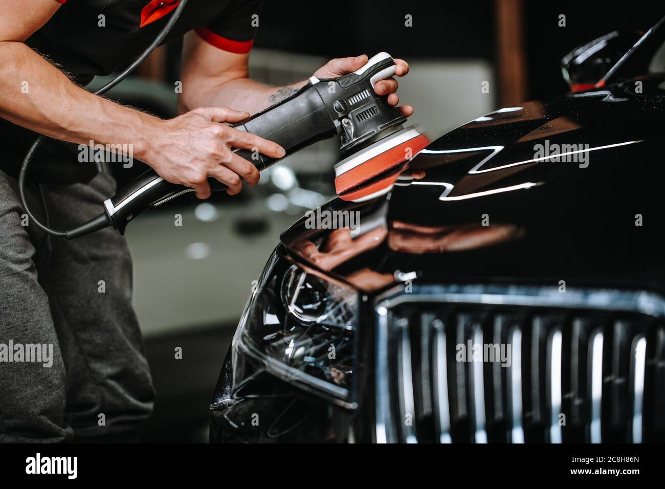 Professional detailing a car in car studio, hands with orbital polisher