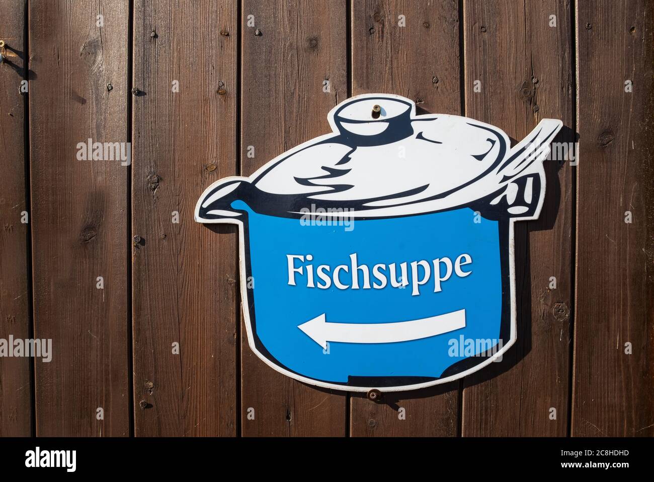 Indication on a cooking pot that fish soup is sold nearby. Wooden Background. (Fischsuppe in engl. Fish soup) Stock Photo