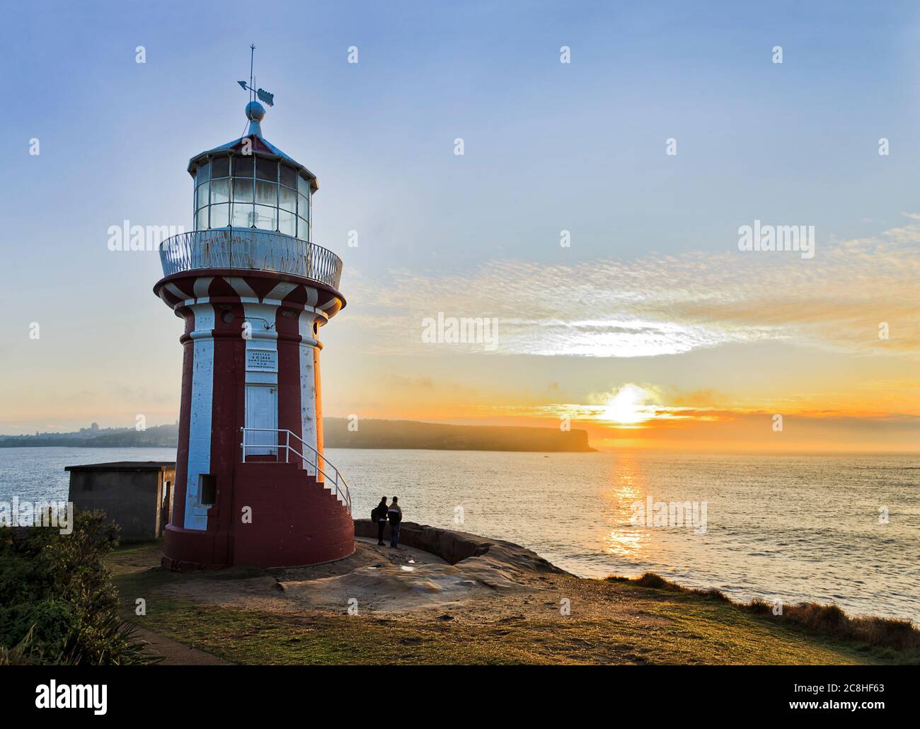 Historic Hornby lighthouse at the entrance to Sydney harbour facing rising sun over Pacific horizon. Stock Photo