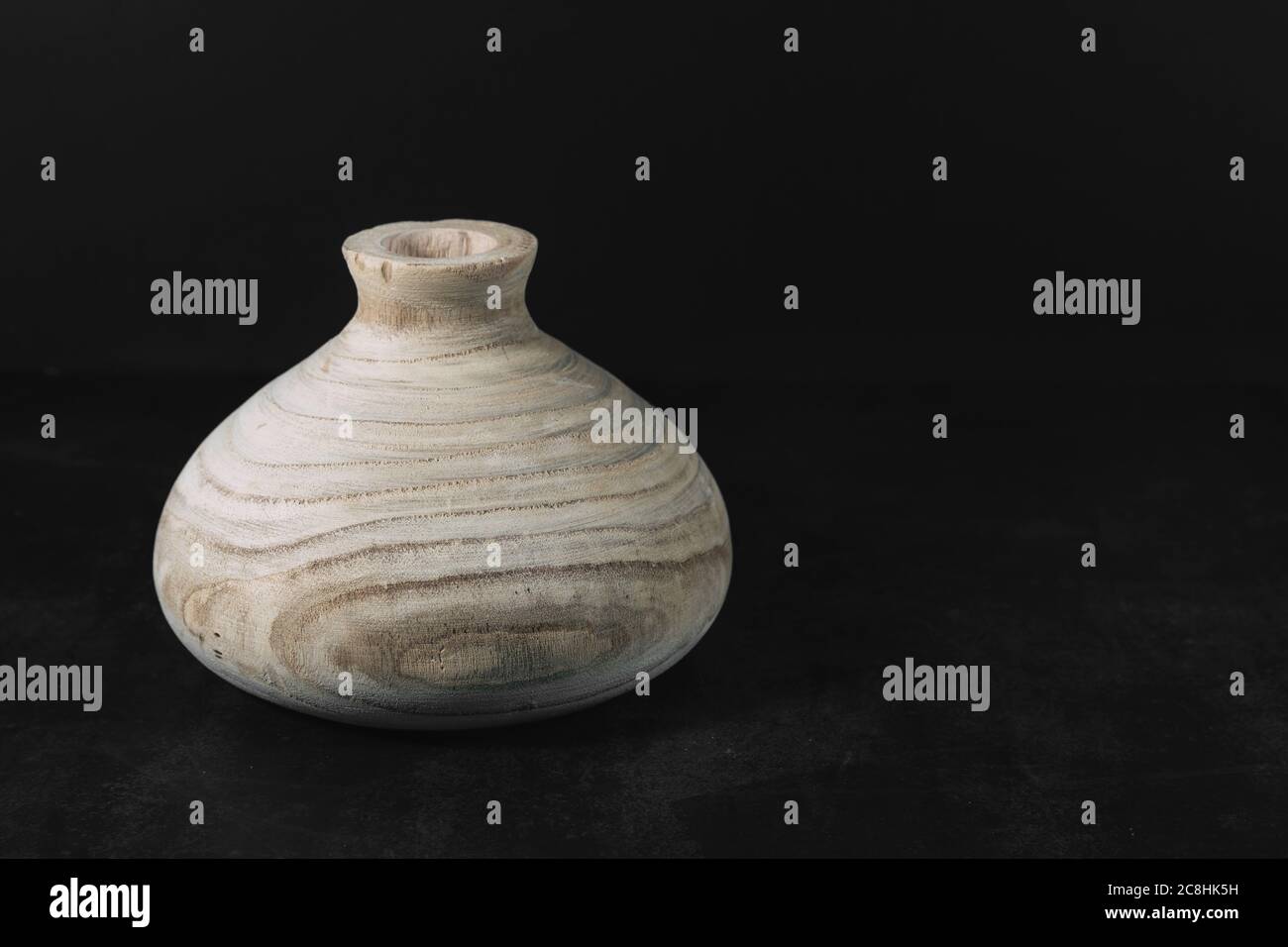 Empty wooden vase on a dark texture table on a black background with space for text. Home interior. Stylish designer vase in light brown in the home c Stock Photo