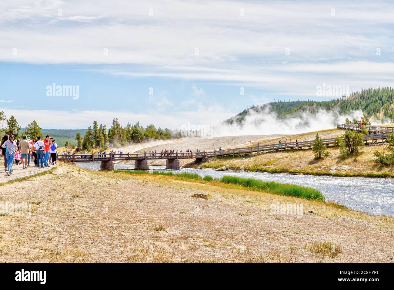 Wyoming, USA - Aug. 24, 2019: Visitors approach the footbridge to Grand Prismatic Spring in Yellowstone National Park with steam rising from the therm Stock Photo