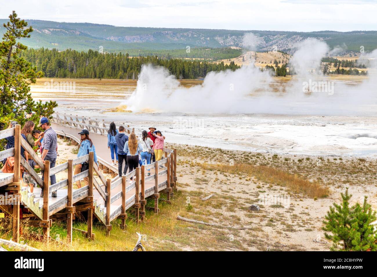 Wyoming, USA - Aug. 24, 2019: Tourists visit an erupting Clepsydra Geyser in the Lower Geyser Basin of Fountain Paint Pot Trail at Yellowstone Nationa Stock Photo