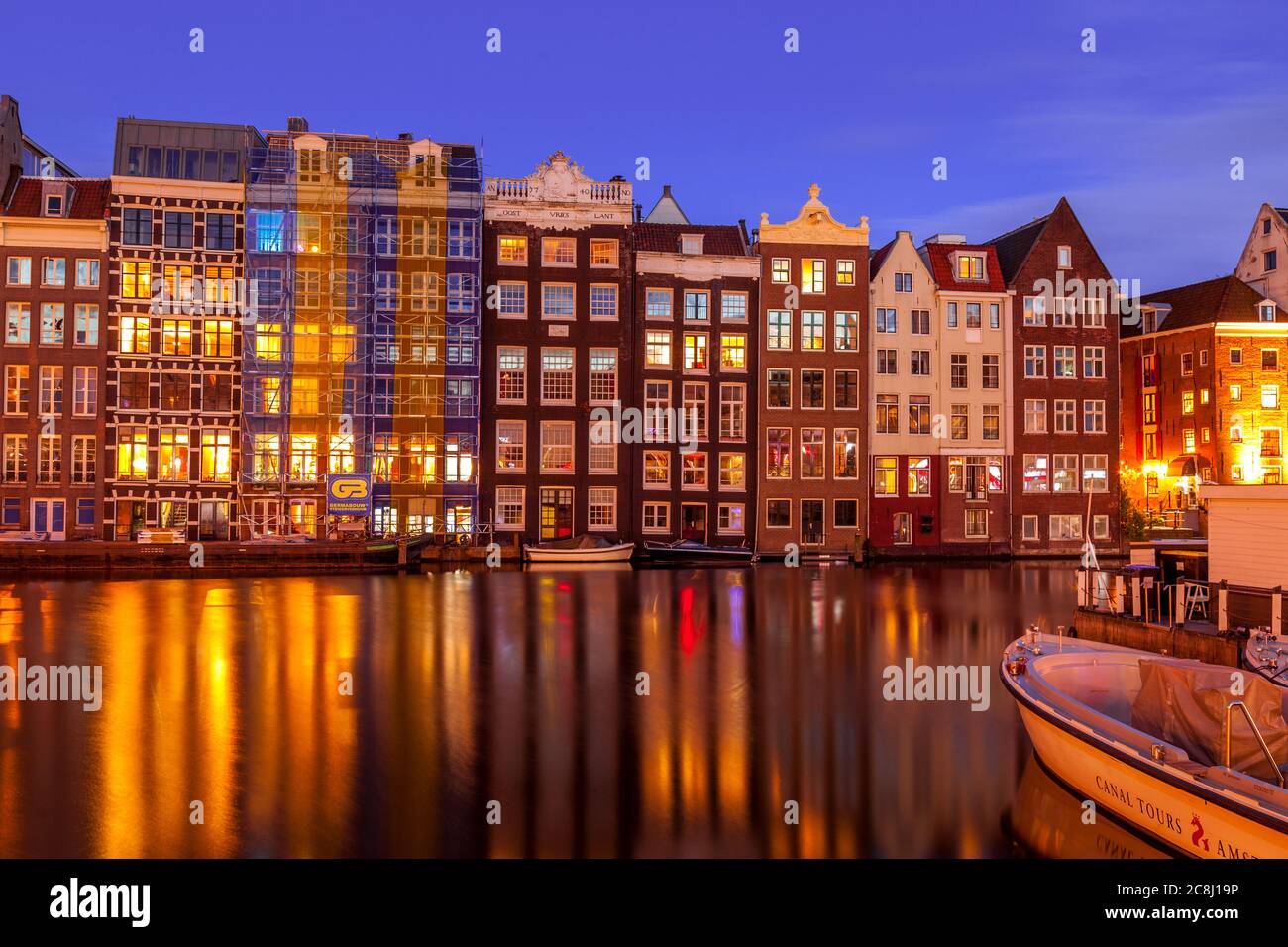 Row houses along a canal in Damrak, Amsterdam Stock Photo
