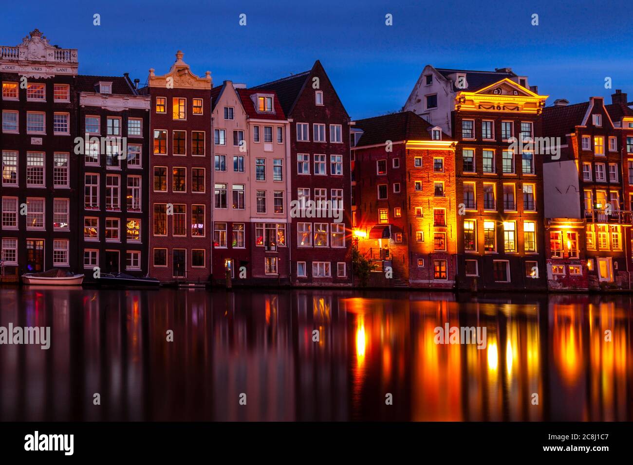 Row houses along a canal in Damrak, Amsterdam Stock Photo