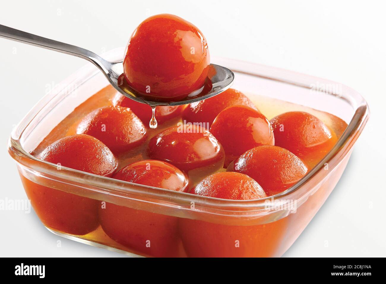 Gulab Jamun served in a square brass plate with pouring sweet syrup - An Indian sweet dish Stock Photo