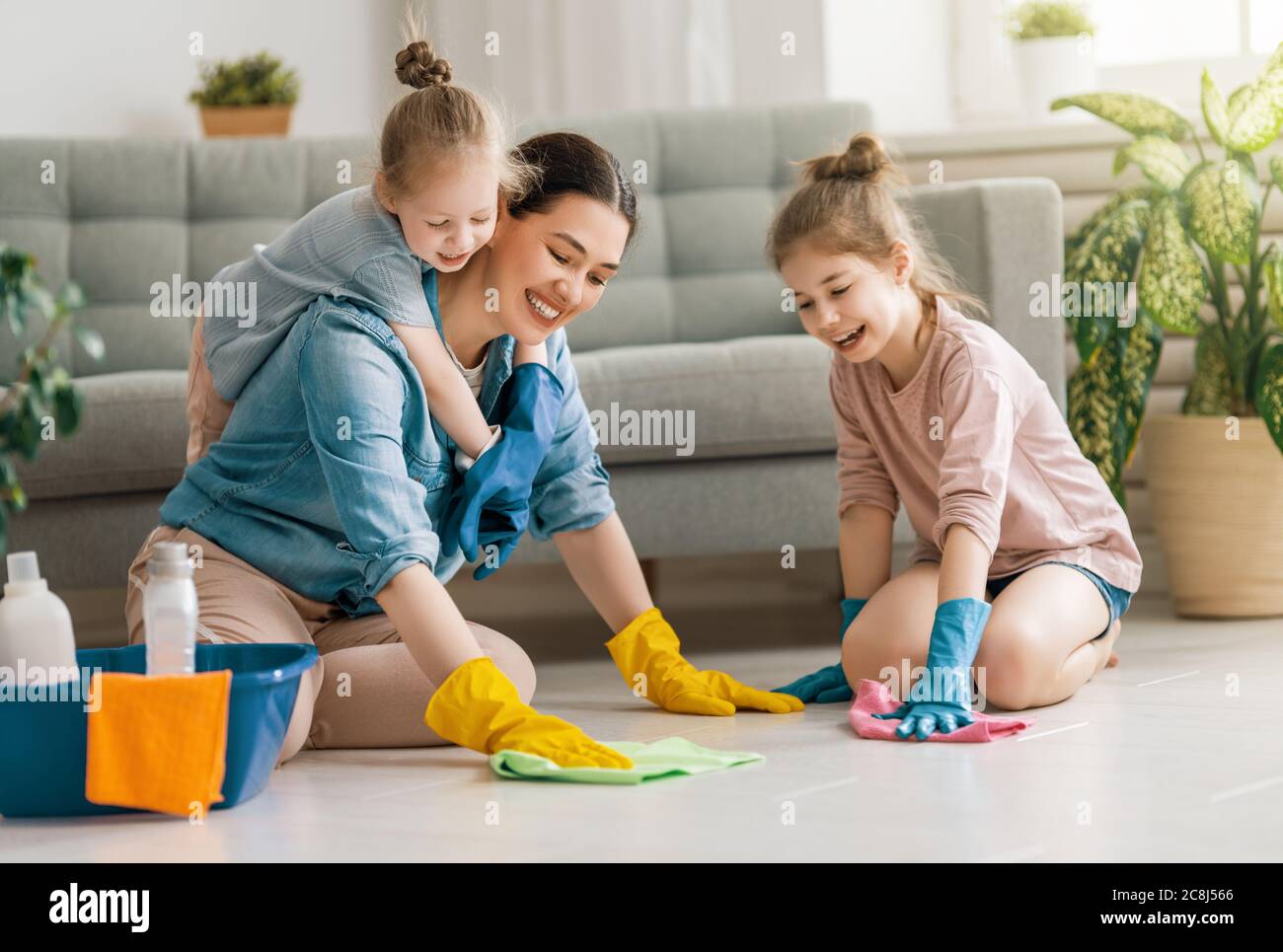 Happy family at home. Mother and daughters doing the cleaning in the