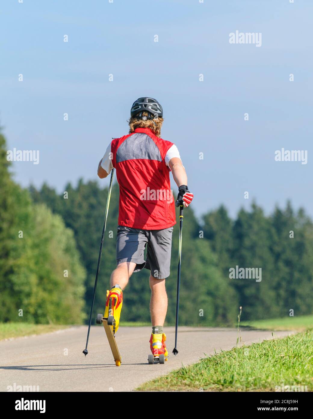 Young man doing a training session on ski rollers in summertime Stock Photo