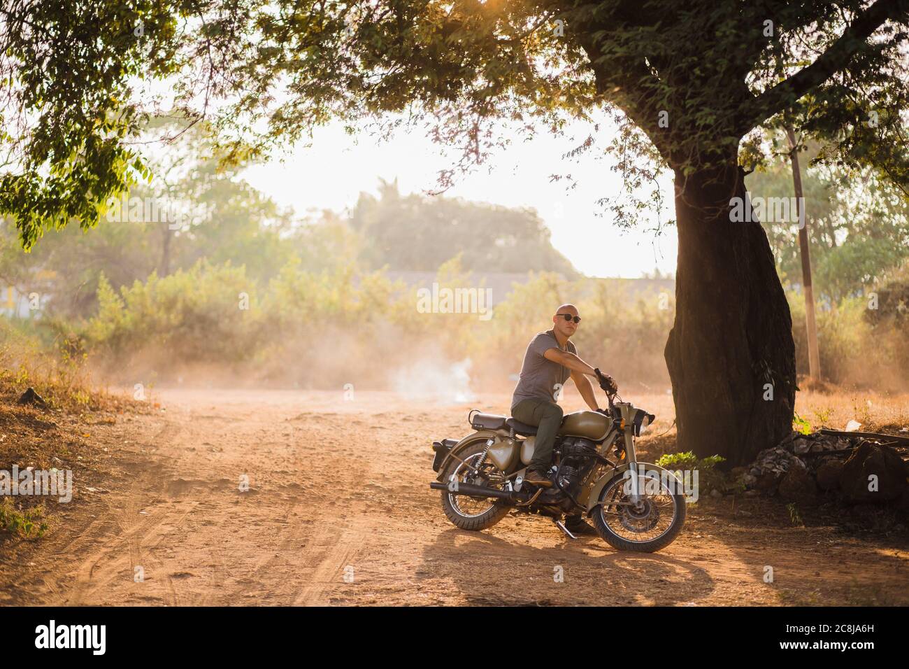 man with glasses on a motorcycle forest in nature Stock Photo