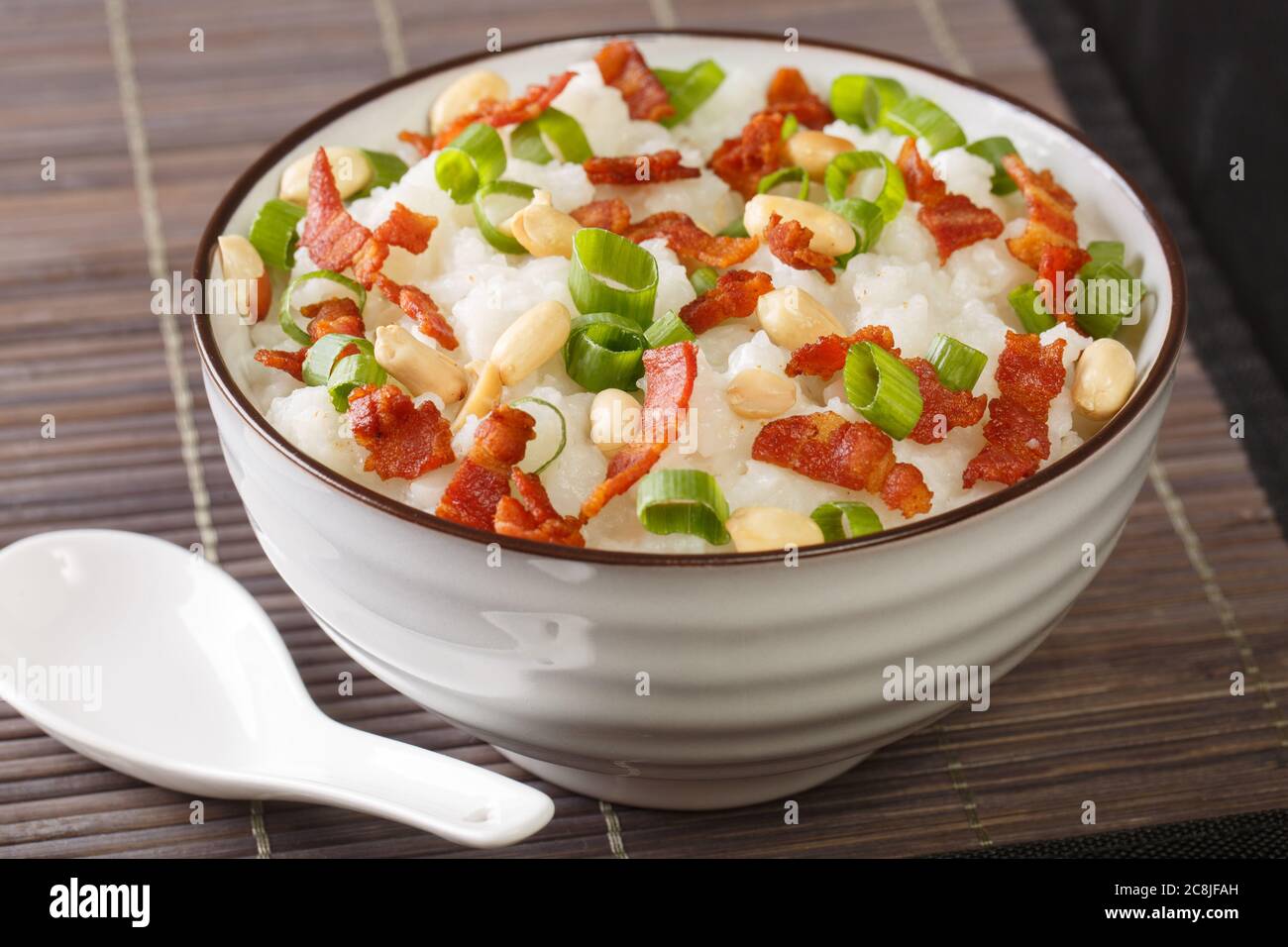 Creamy, slightly salty, and thick like porridge, jook is a popular Chinese breakfast. Rice congee is comfort food close-up in a bowl on the table. Hor Stock Photo