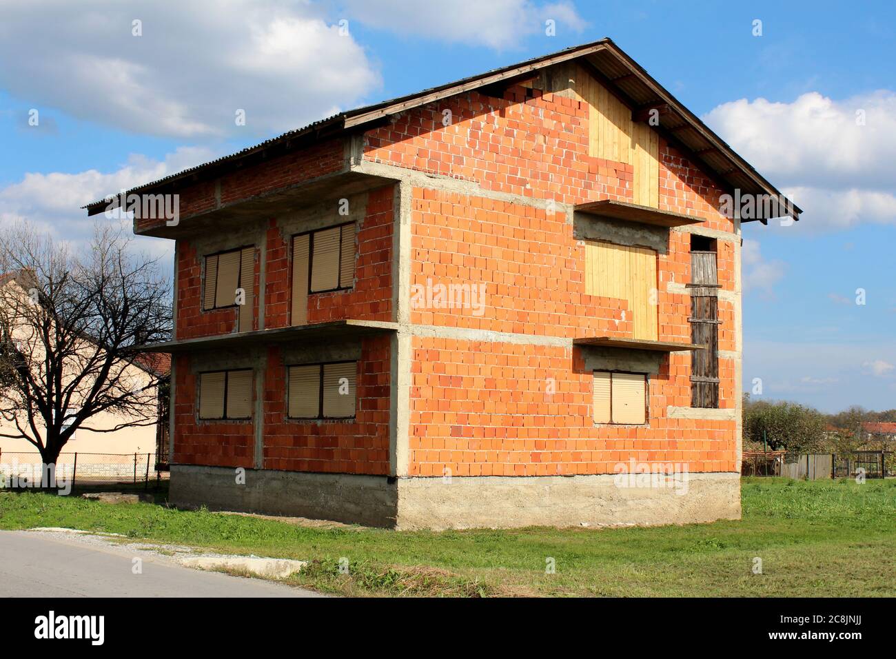 Facade of an unfinished two-story house with no red brick windows