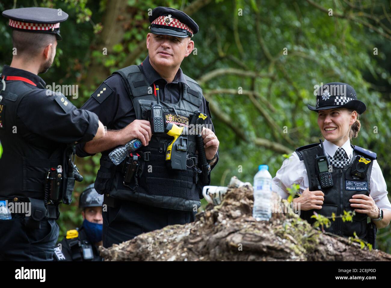 Denham, UK. 24 July, 2020. Police officers from City of London Police and the Metropolitan Police chat alongside the river Colne during a large policing operation also involving Thames Valley Police and Hampshire Police to prevent environmental activists from HS2 Rebellion from attempting to hinder the destruction of an ancient alder tree in connection with works for the HS2 high-speed rail link in Denham Country Park. Credit: Mark Kerrison/Alamy Live News Stock Photo