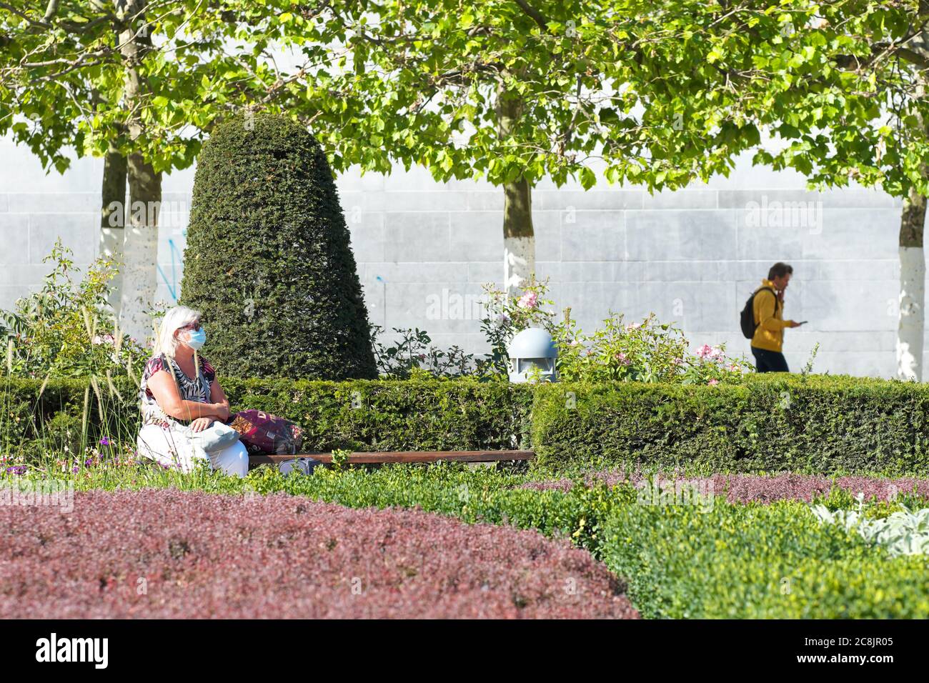Brussels, Belgium a woman wearing a coronavirus facemask sits in the beautiful Tuin van de Kunstberg park in Brussels city centre in July 2020 Stock Photo