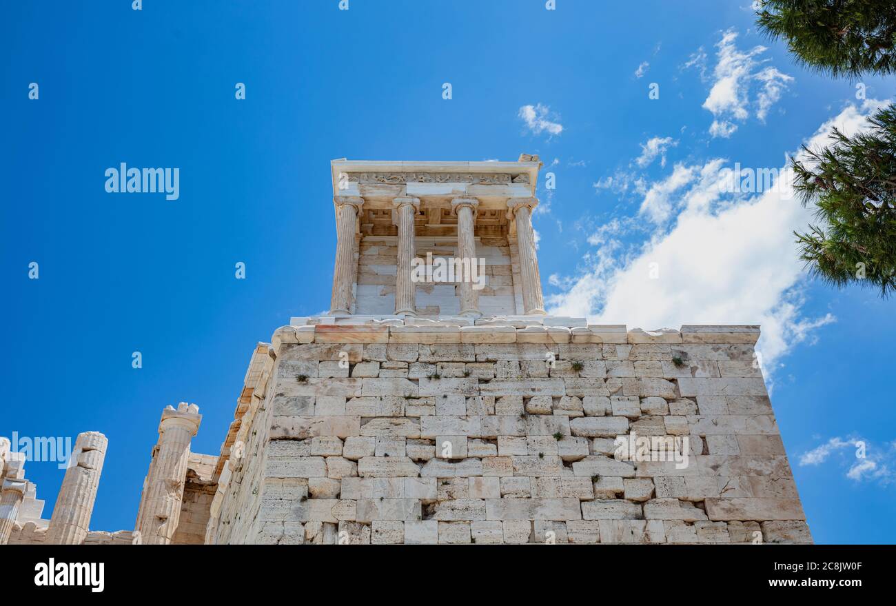 Athens Acropolis, Greece landmark. The Temple of Athena Nike low angle view at Propylaea gate entrance, blue cloudy sky in a spring sunny day. Stock Photo