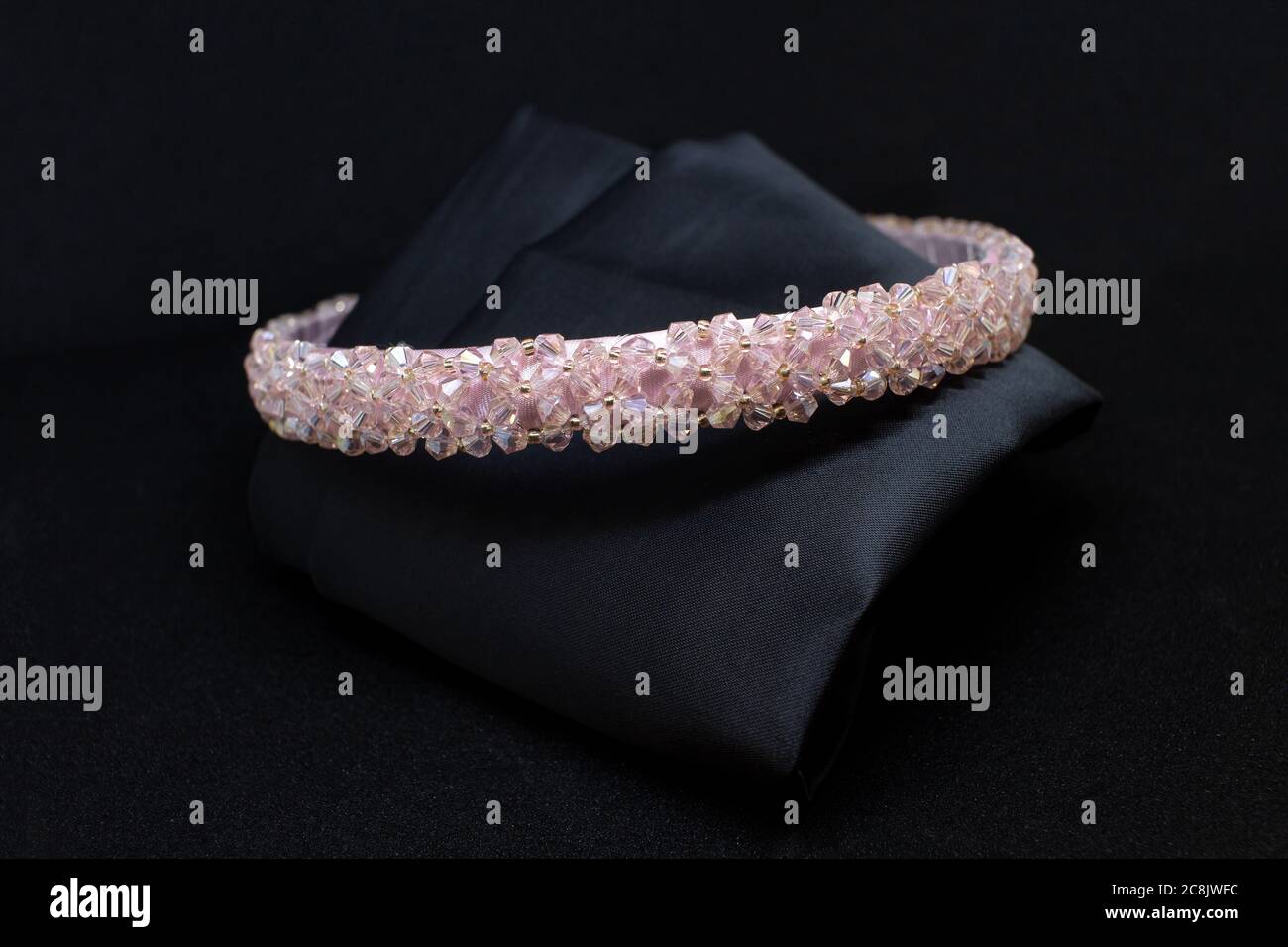 Pink gemstones diamonds hair band tiara on black background. Jewelry display isolated concept Stock Photo