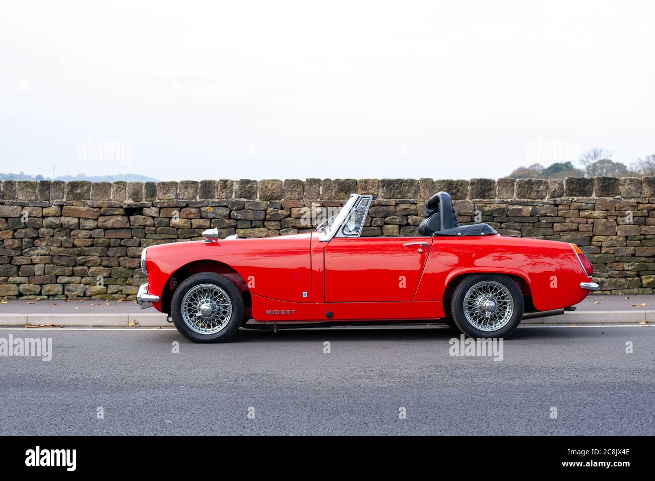 MG Midget parked by a stone wall on a country road Stock Photo