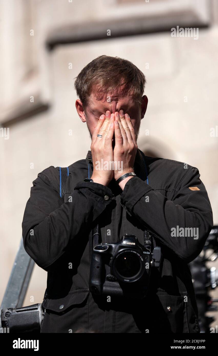 A press photographer covers his face as he waits for the arrival of actor Johnny Depp at the Royal courts of justice Stock Photo