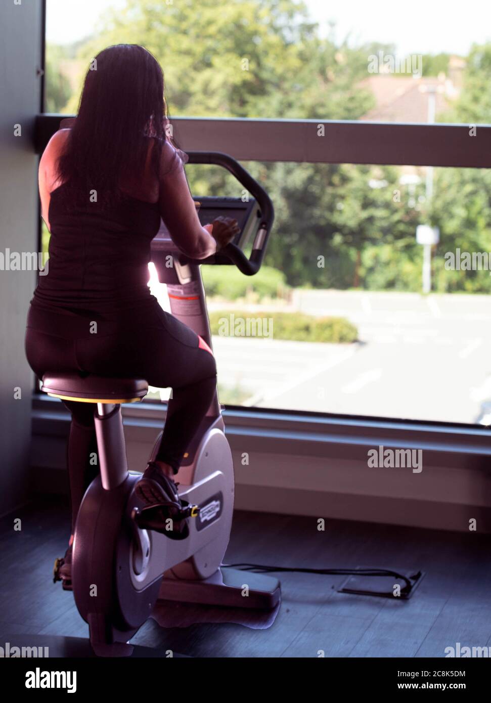 Black women exercising on exercise bike Stock Photo