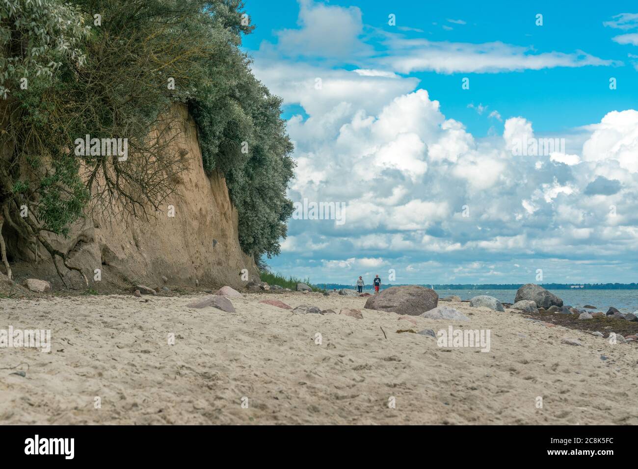 Poel, Mecklenburg, Germany - july 16, 2020: a man and a woman waking on the beach at the sandstone cliffs near Schwarzer Busch Stock Photo