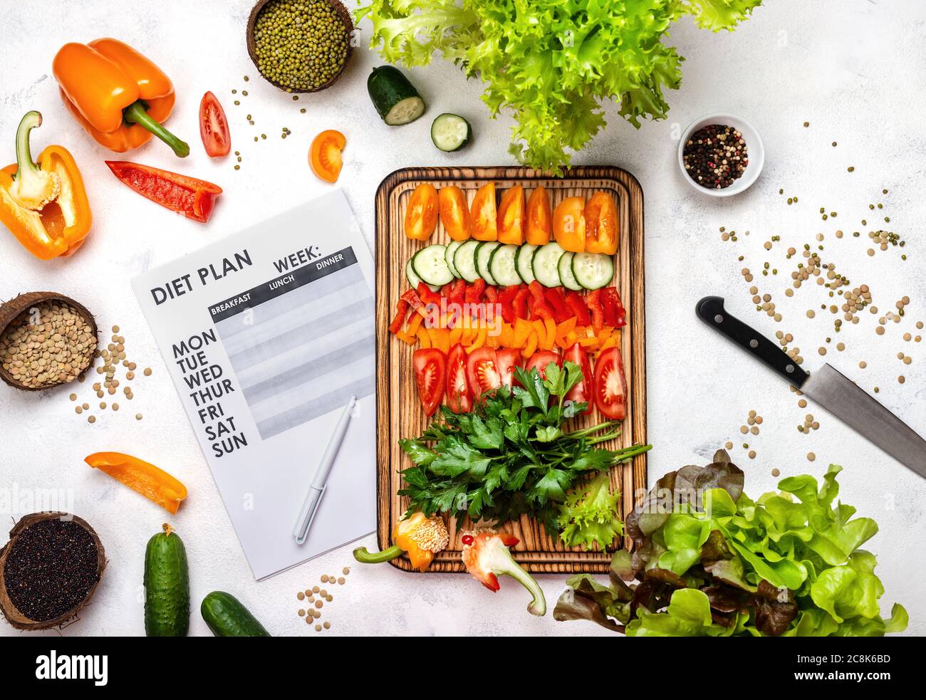 Diet plan and chopped fresh vegetables on wooden board. Stock Photo