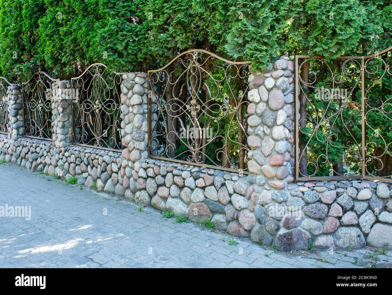 beautiful patterned wrought iron fence with stone pillars on sunny