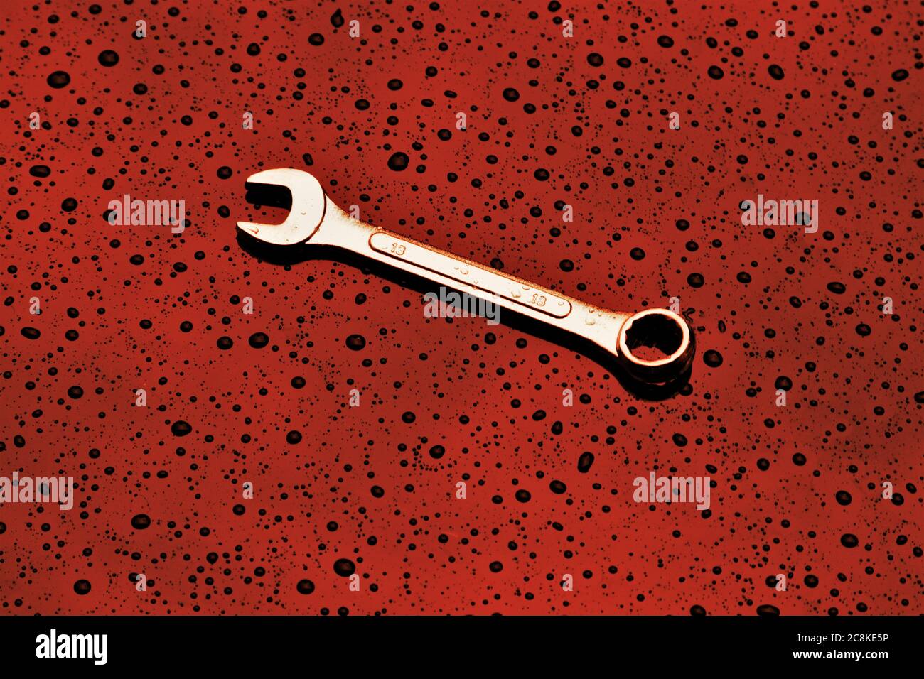 A single spanner on a textured red background Stock Photo