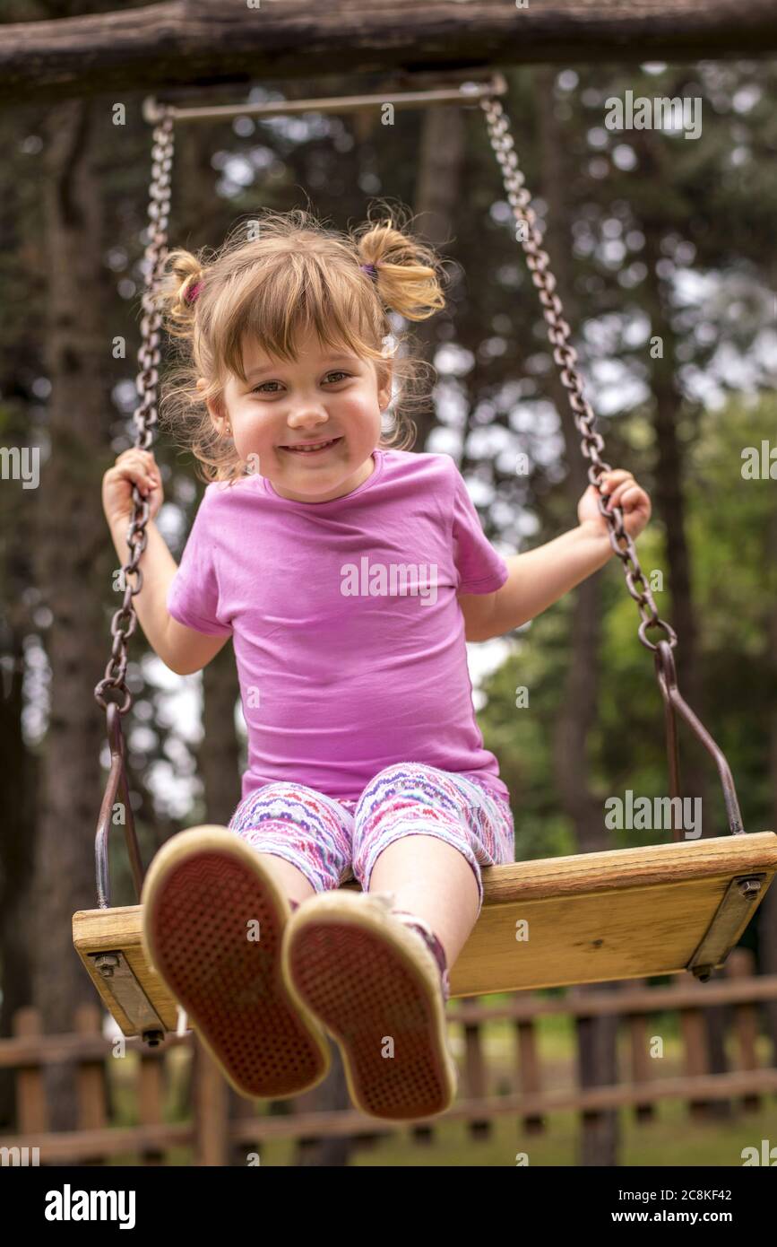 Vertical shallow focus shot of a young female swinging on a swing in  playground Stock Photo - Alamy