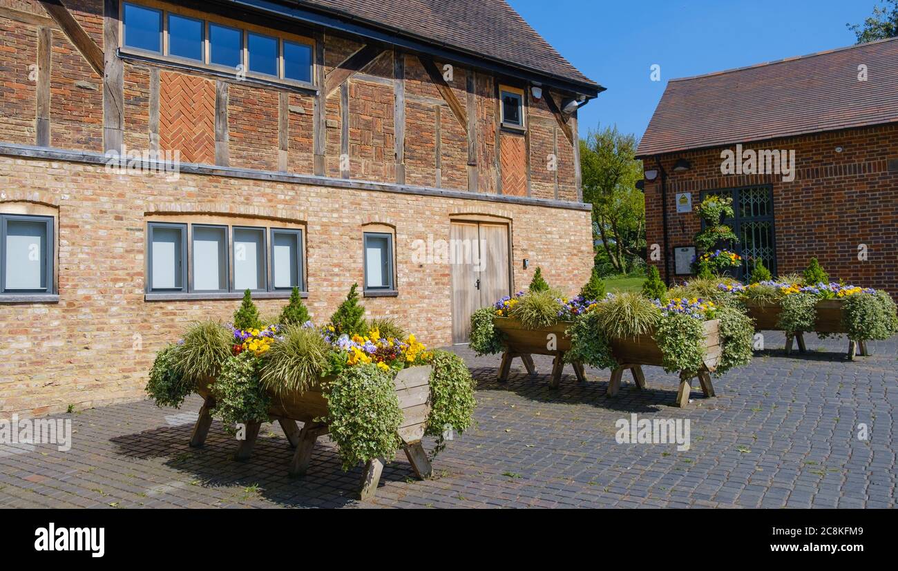 The Stables, 17th century timber framed building, with wooden planters, purple & yellow flowers & foliage, Eastcote House Gardens , Eastcote,  London. Stock Photo