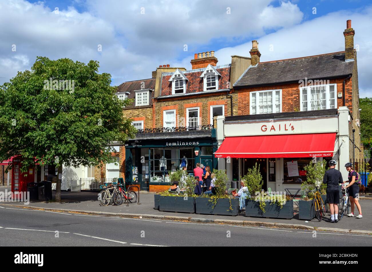 A shop and a bakery in Dulwich Village with people enjoying the summer sunshine. Dulwich is in south London. Stock Photo