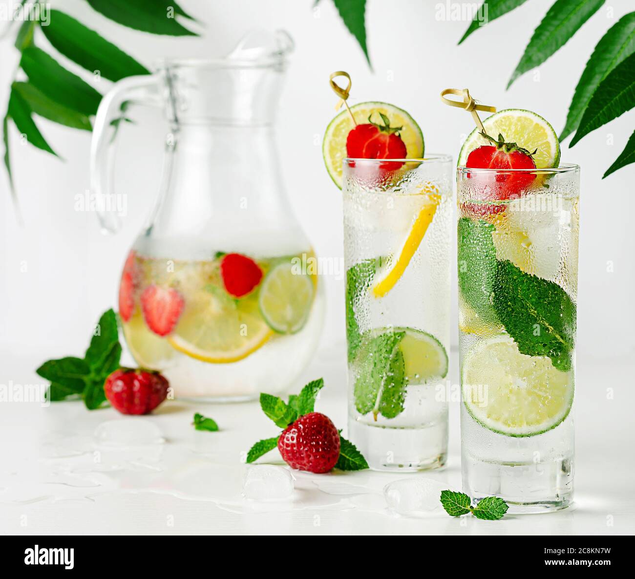Refreshing infused water with lime, lemon, mint and strawberry on white background. Stock Photo