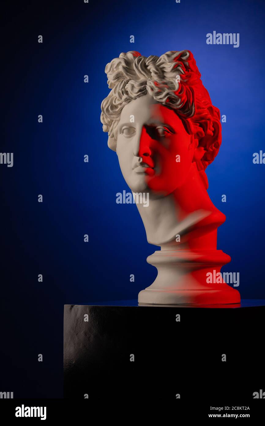 White plaster statue of a bust of Apollo Belvedere in red light on a