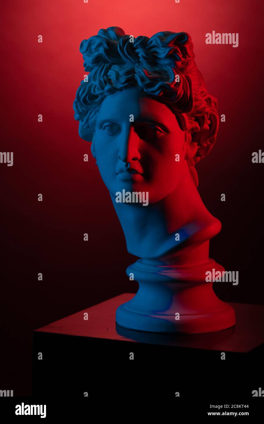 Plaster statue bust of Apollo Belvedere in red and blue light on a red