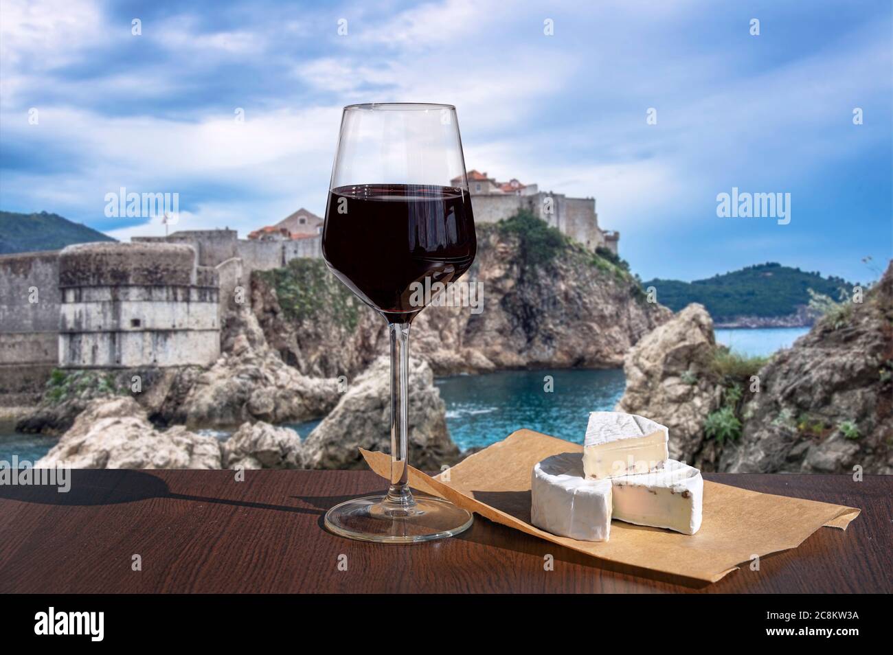 Glass of red wine with brie cheese with view of the fortress walls