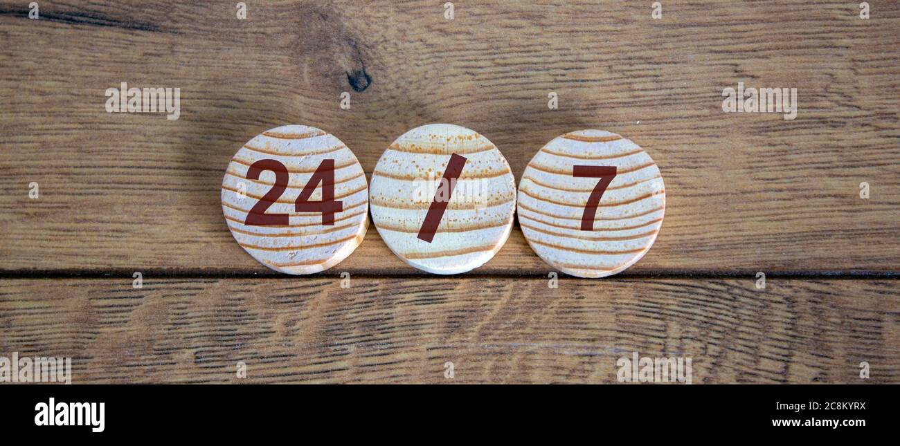 Numbers 24/7. Wooden small circles with letters on wood background. Concept image. Stock Photo